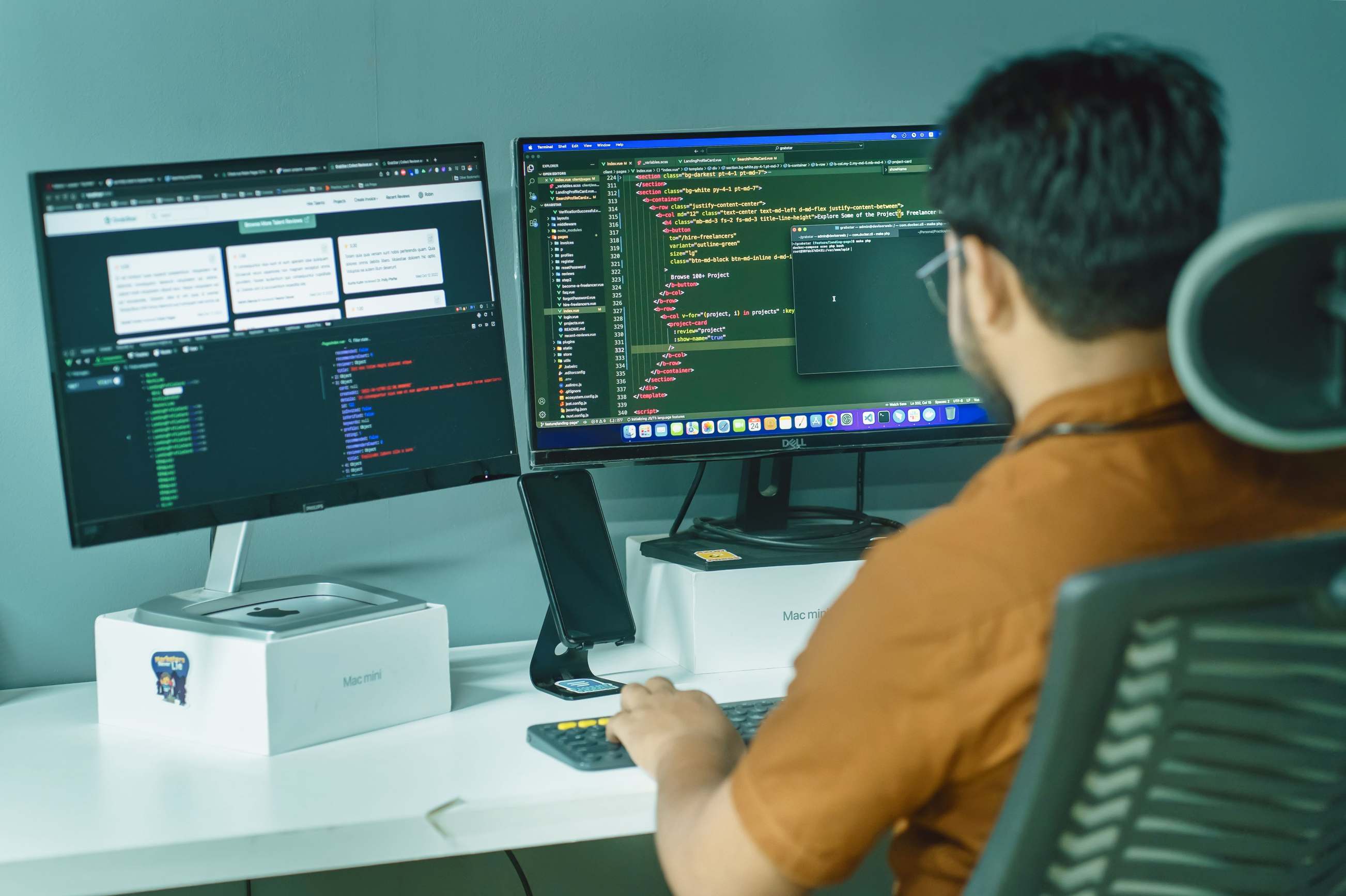 People working at computers in an office setting — software developer coding on dual monitors in a modern office