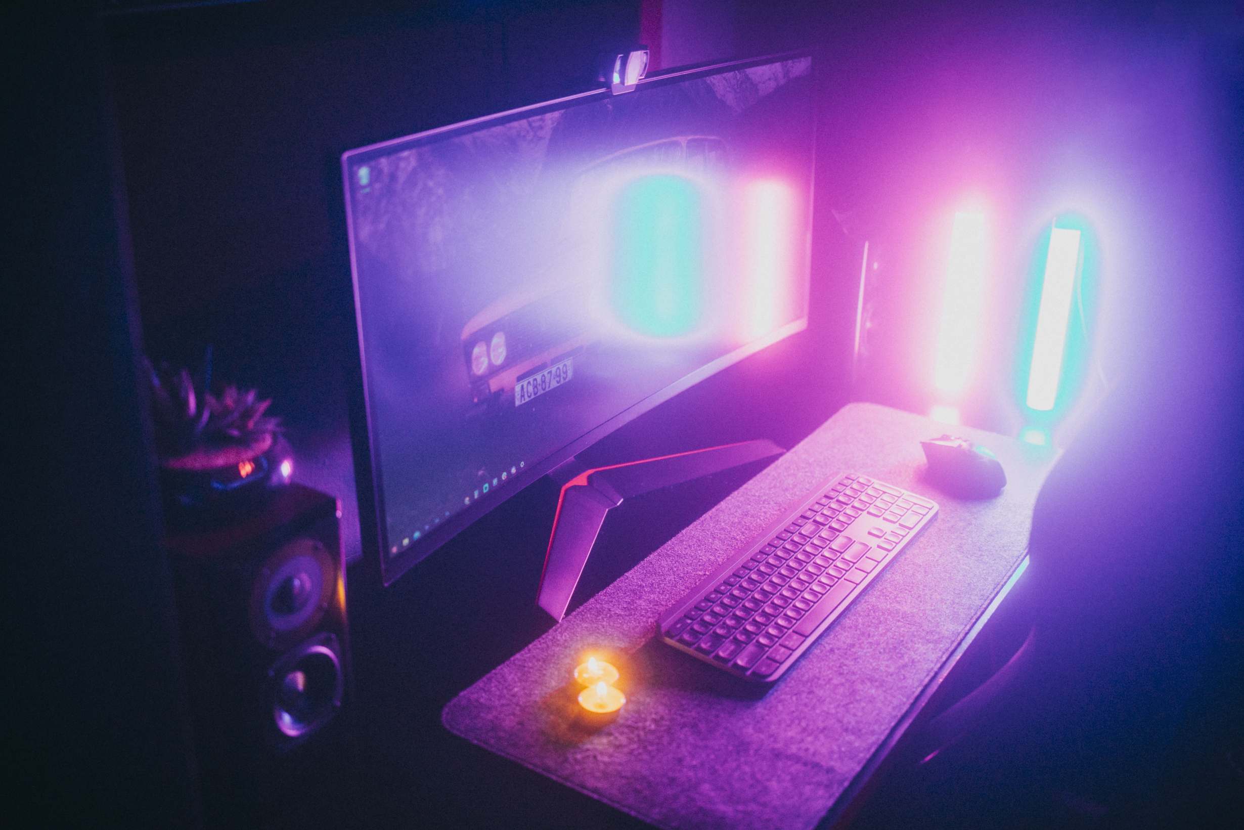 Laptop and monitors on a desk in a dim office with keyboard and monitor in a dark room
